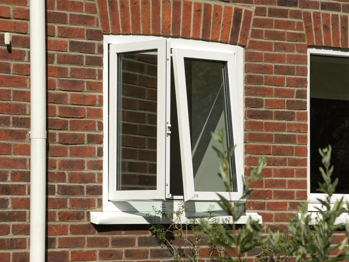 A white uPVC casement window fitted in a modern brick wall